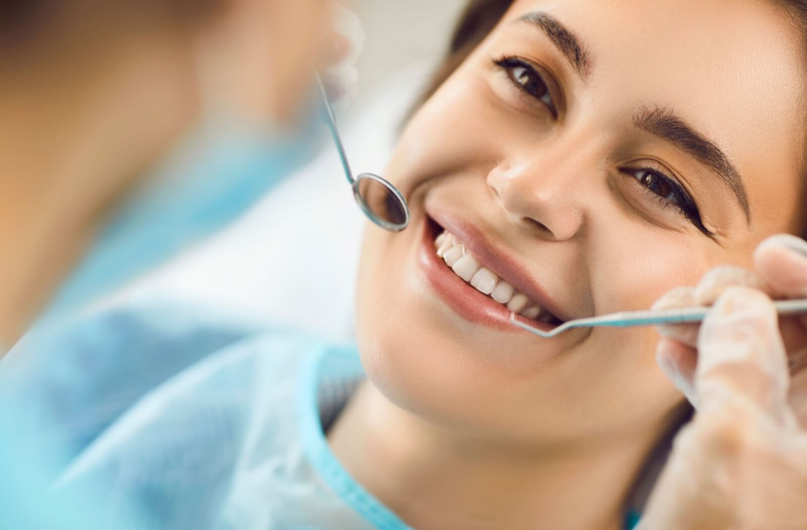 Smiling patient during a dental exam with a dentist using tools to ensure clean healthy teeth and proper oral care