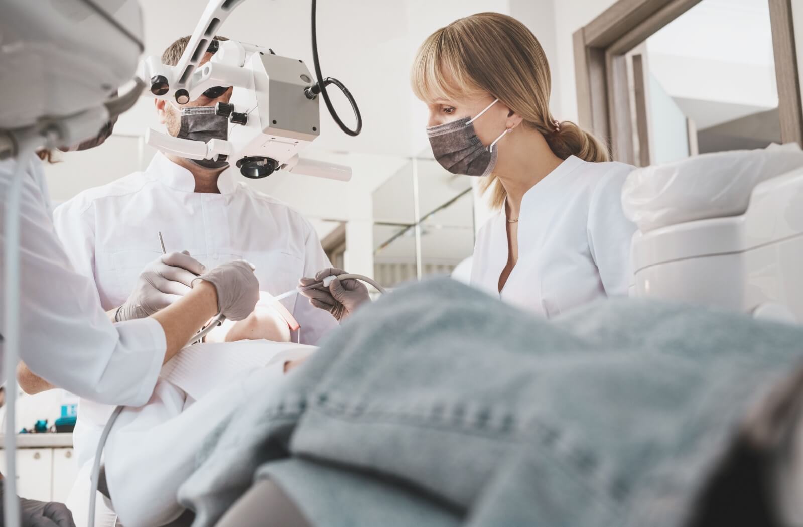 Dental team performing a procedure with magnification tools focusing on restorative dentistry and cavity treatment