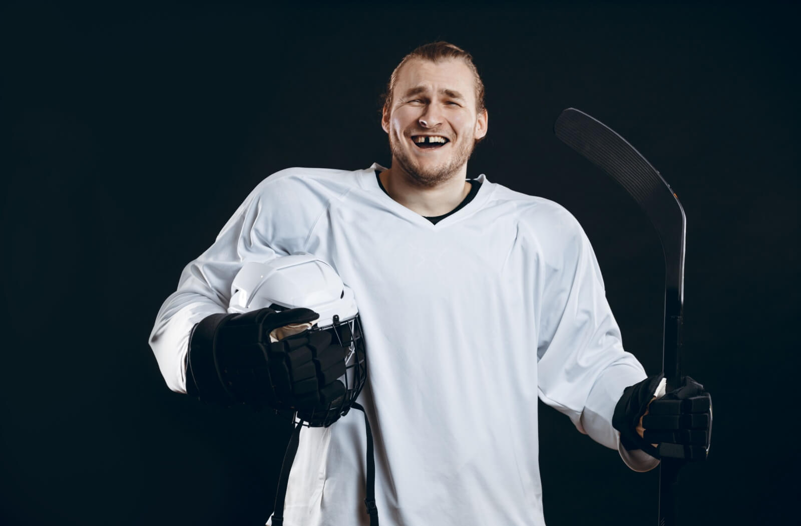 A person wearing a hockey jersey smiles, revealing a missing tooth.