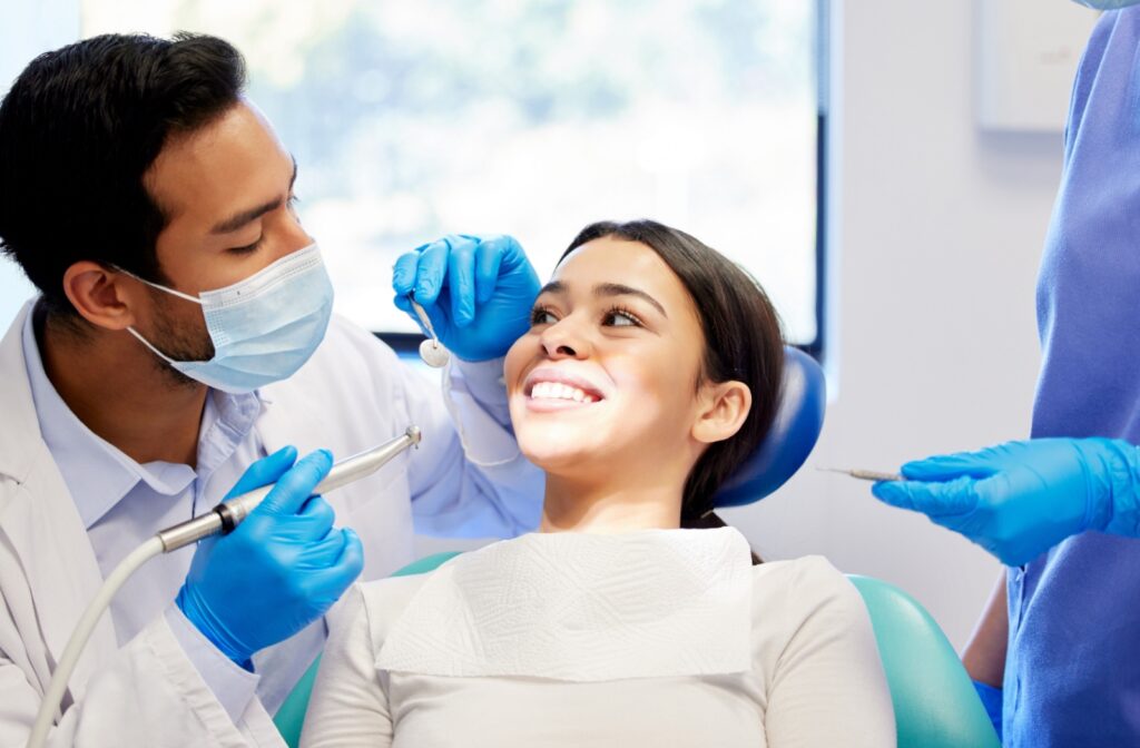 A dental patient looking over at their dentist, smiling during a dental cleaning.