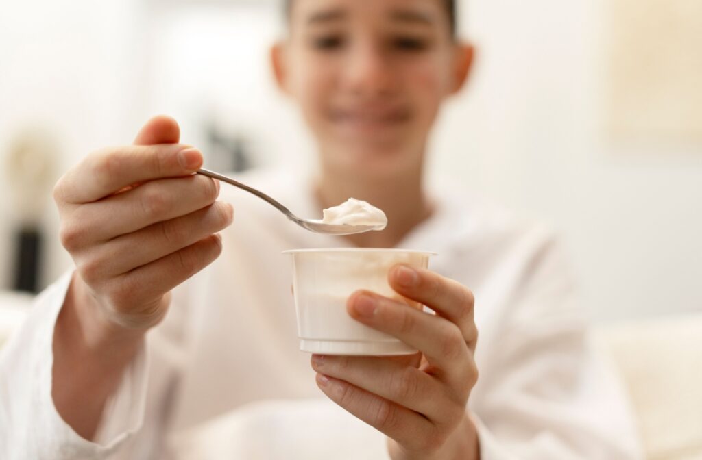 A person eating yogurt after having dental freezing.